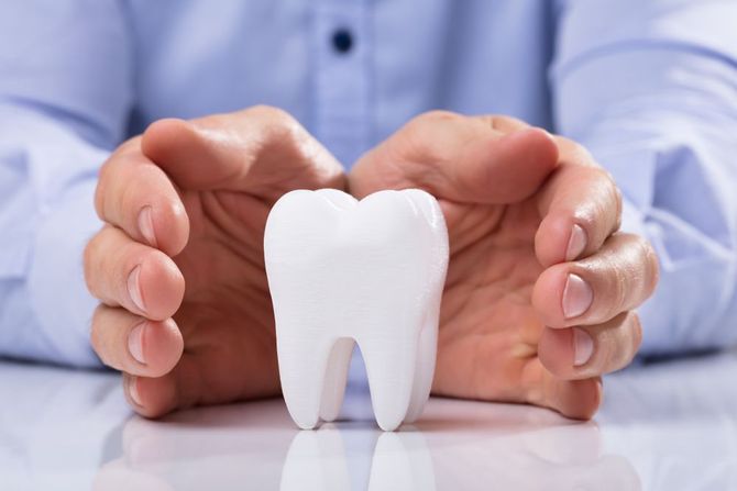 A Person is Holding a White Tooth in Their Hands — Graham Johnson Dental Surgery In Beresfield, NSW