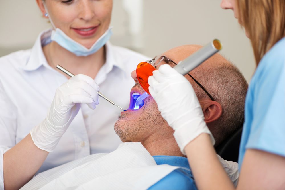 A Man is Getting His Teeth Examined by a Dentist — Graham Johnson Dental Surgery In Beresfield, NSW