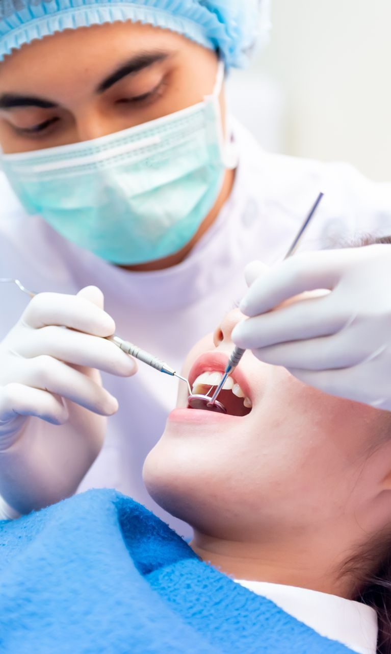 A Dentist is Examining a Woman 's Teeth in a Dental Office — Graham Johnson Dental Surgery In Beresfield, NSW