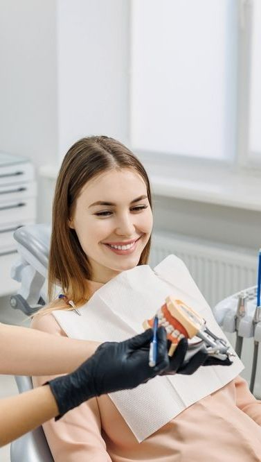 A Woman is Smiling While Sitting in a Dental Chair — Graham Johnson Dental Surgery In Beresfield, NSW