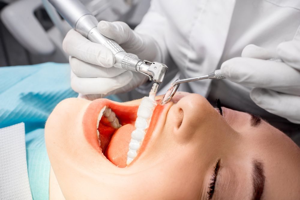 A Woman is Getting Her Teeth Cleaned by a Dentist — Graham Johnson Dental Surgery In Beresfield, NSW