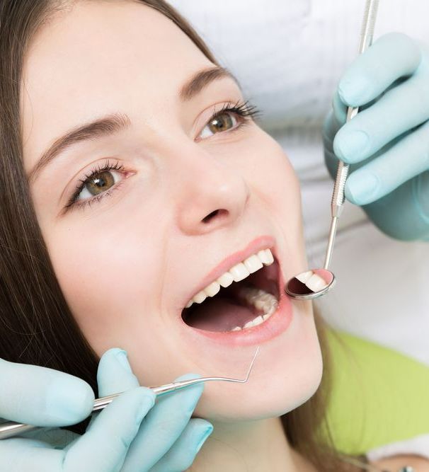 A Woman is Getting Her Teeth Examined by a Dentist — Graham Johnson Dental Surgery In Beresfield, NSW