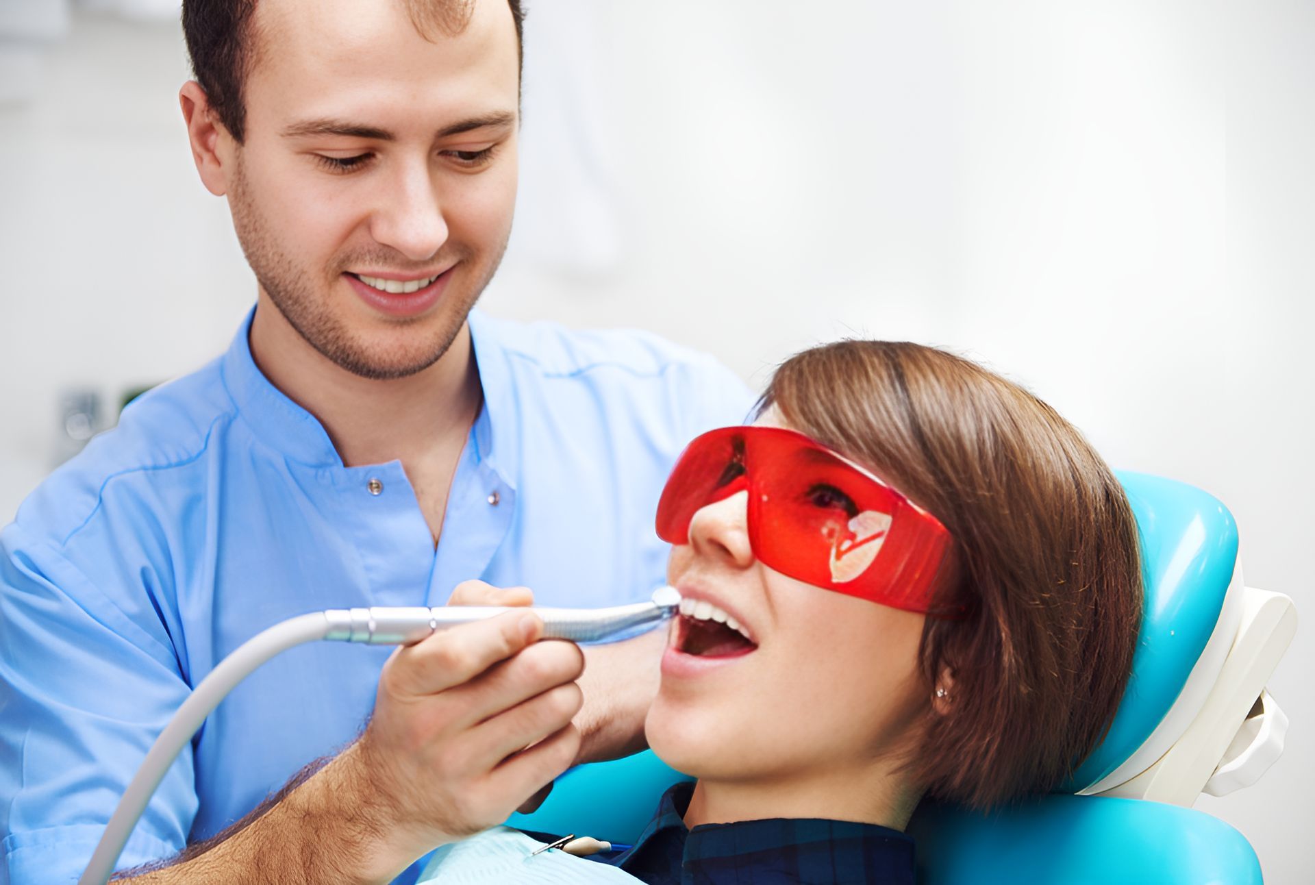 A Woman is Sitting in a Dental Chair Getting Her Teeth Whitened by a Dentist — Graham Johnson Dental Surgery In Jesmond, NSW