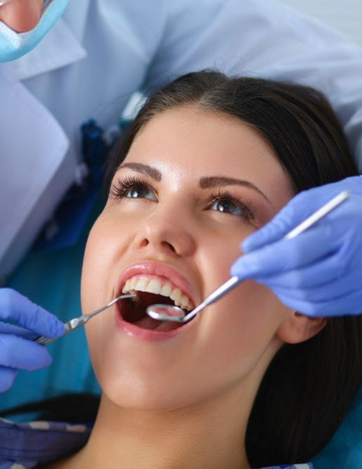 A Woman is Getting Her Teeth Examined by a Dentist — Graham Johnson Dental Surgery In Beresfield, NSW