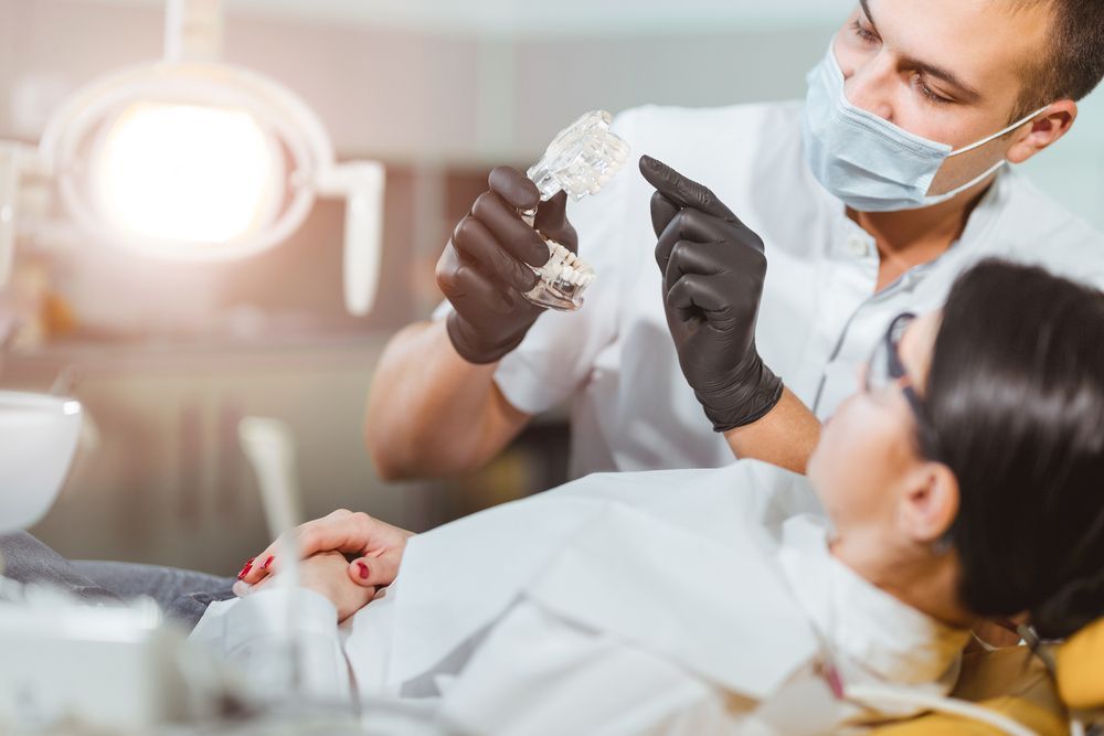 A Woman is Sitting in a Dental Chair While a Dentist Examines Her Teeth — Graham Johnson Dental Surgery In Beresfield, NSW