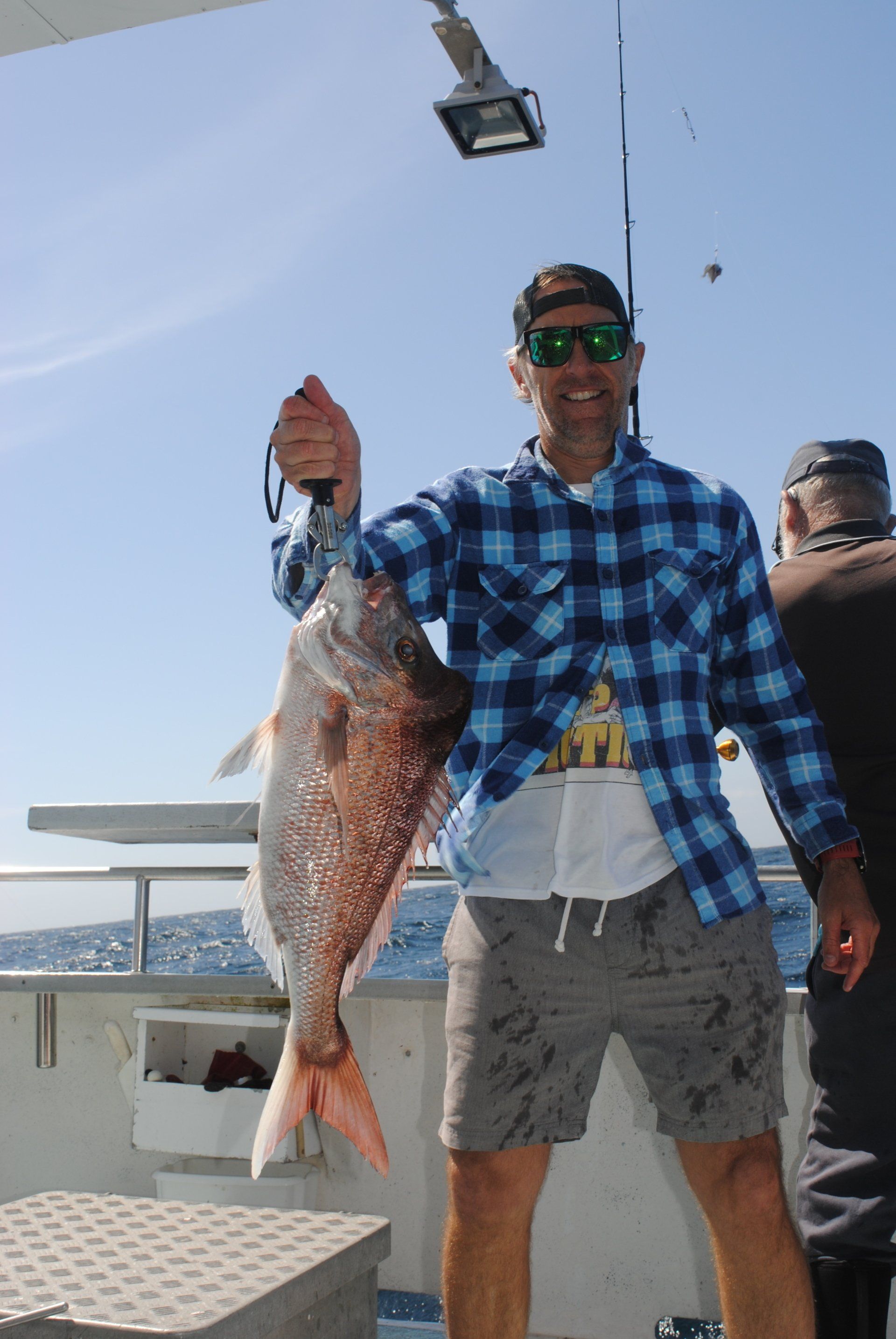 A man in a plaid shirt is holding a large fish