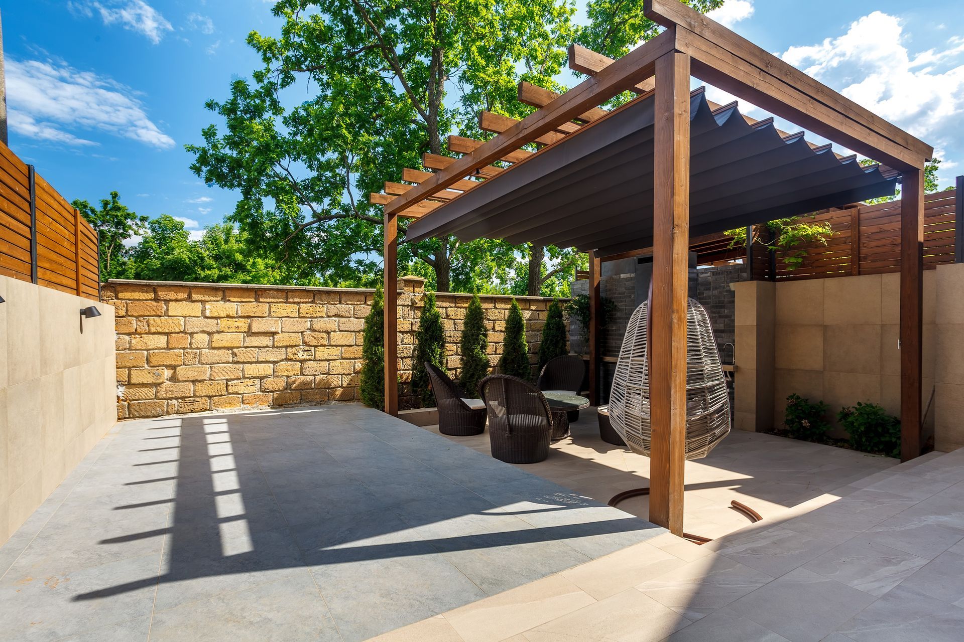 Outdoor patio with a wooden pergola, brick wall, and modern seating.