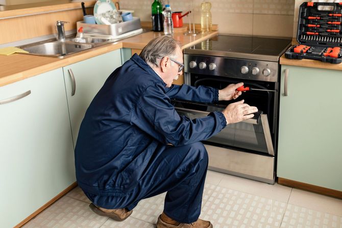 A Worker is Repairing an Oven in the Kitchen — Fairport, NY — Terry Rickner Appliance Service