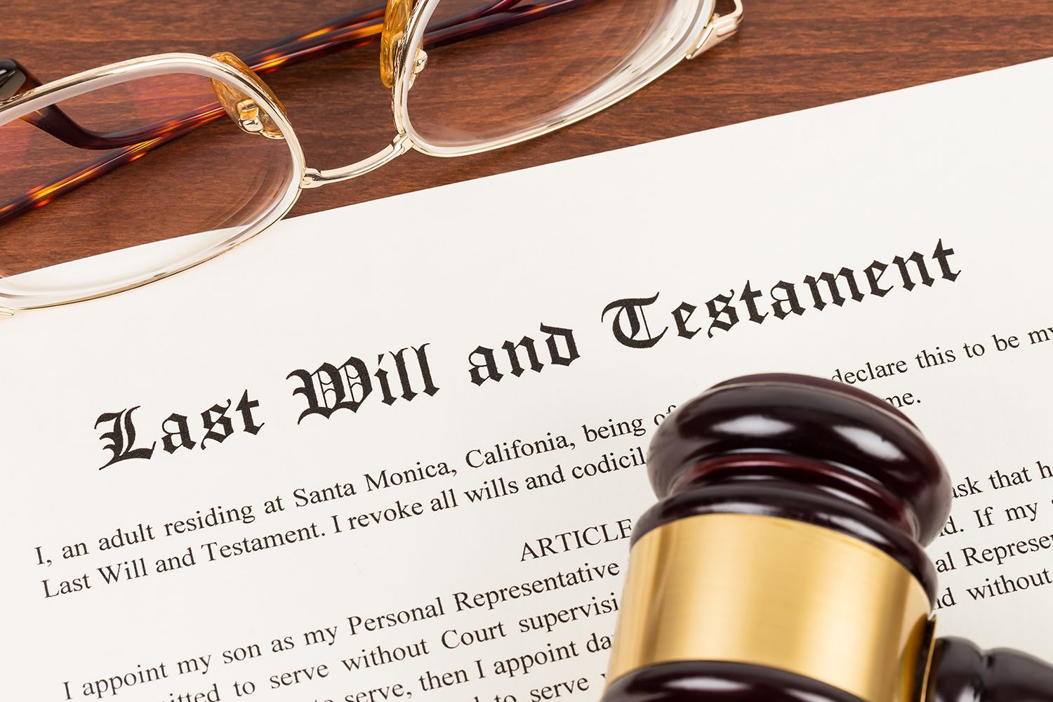 Last Will and Testament document with a gavel and glasses on a wooden surface.