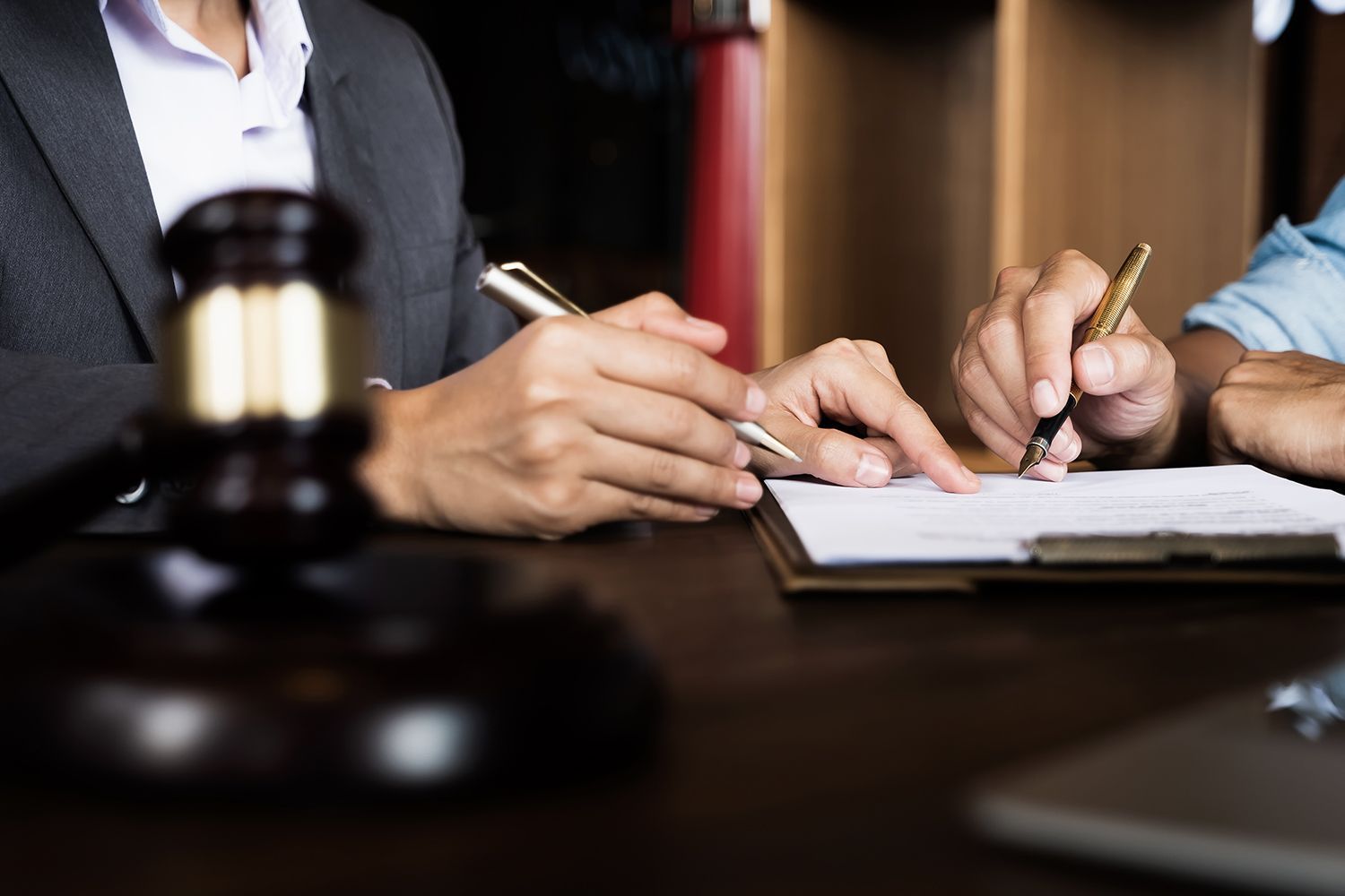 Hands pointing at a document, beside a gavel, suggesting a legal consultation.