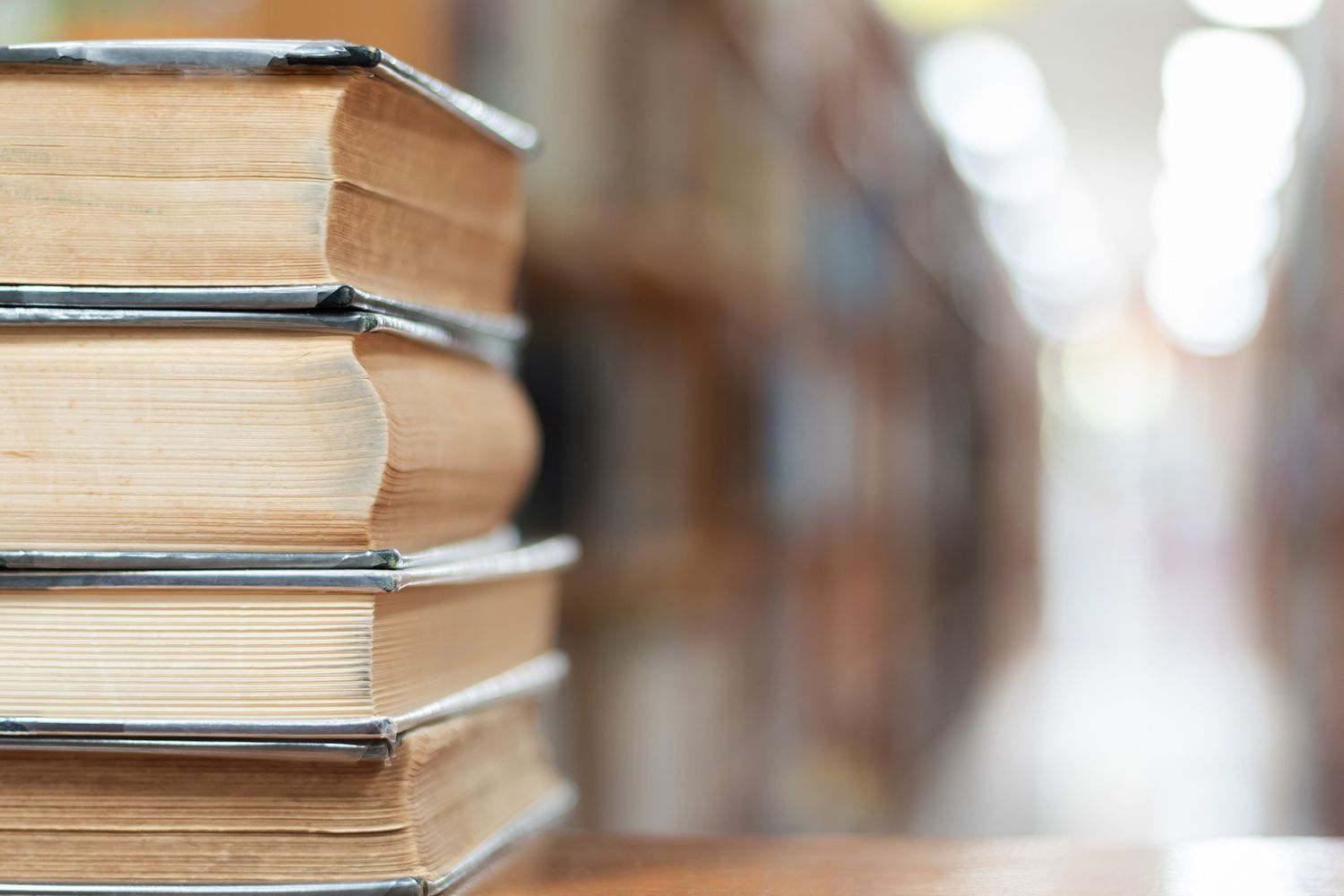 Stack of books on a table with a blurred library background.