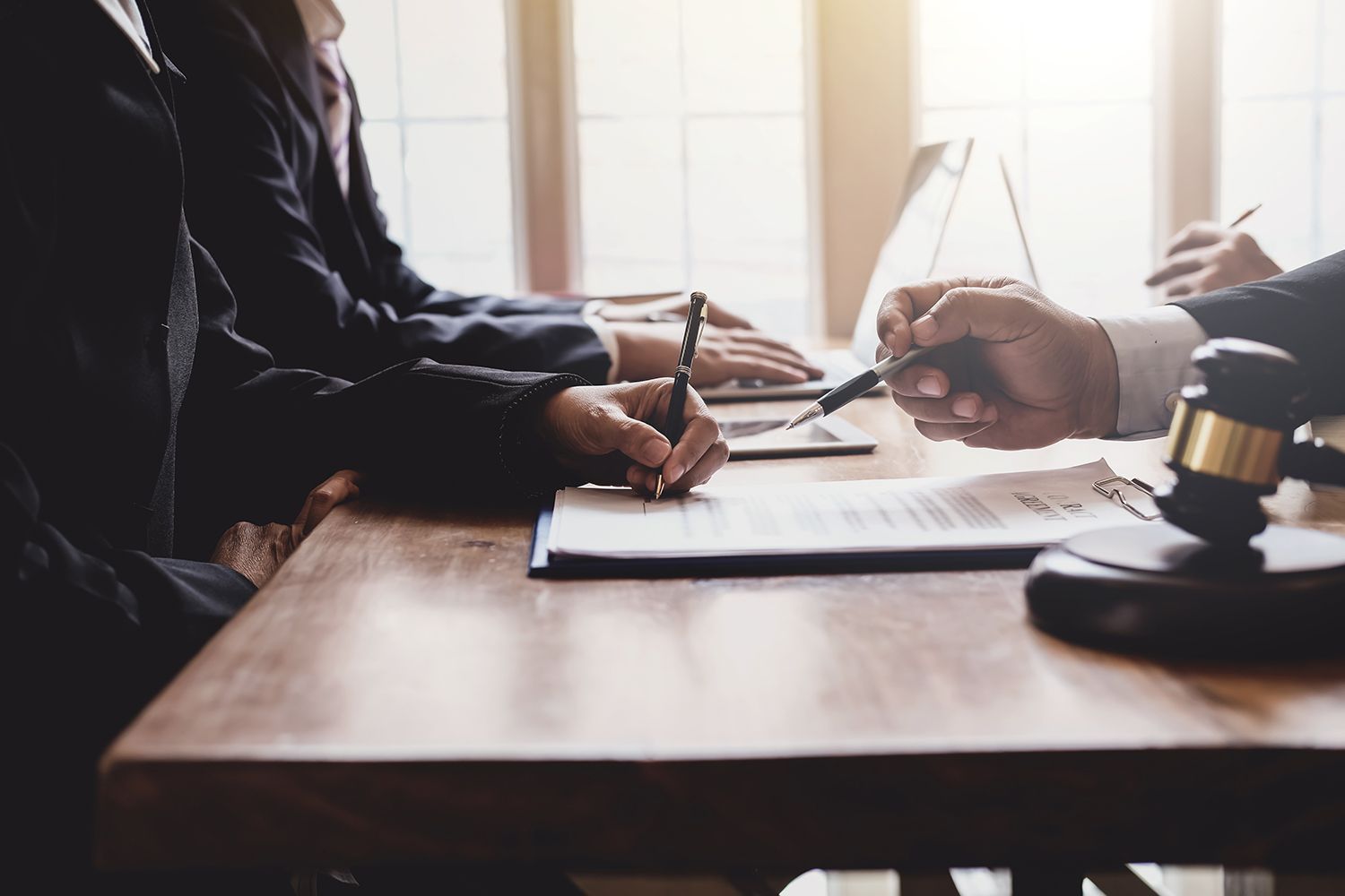 People in suits at a table reviewing documents with a gavel. People in suits at a table reviewing documents with a gavel.