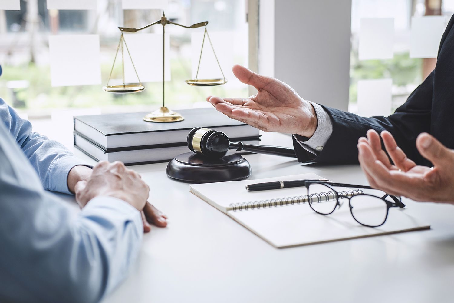 Lawyer explains something to a client, scales of justice and gavel on desk.