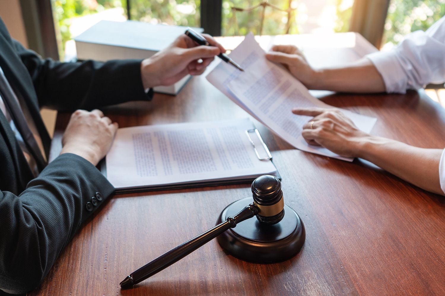 Lawyer pointing at documents with client; gavel on the table.