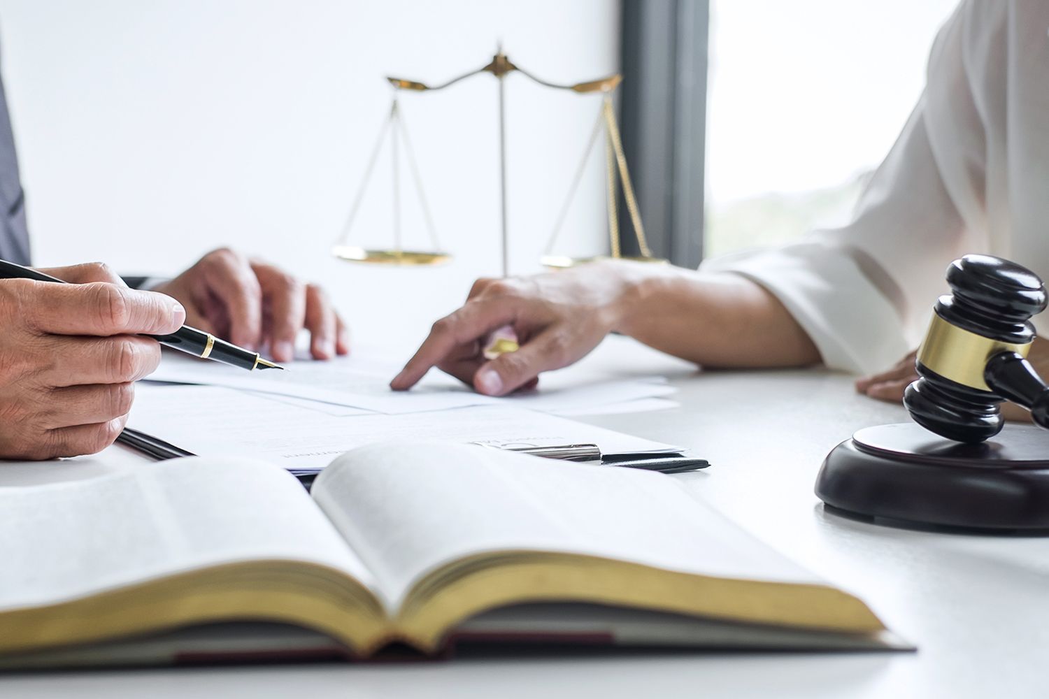 Lawyer and client review documents, scales of justice and gavel on desk.