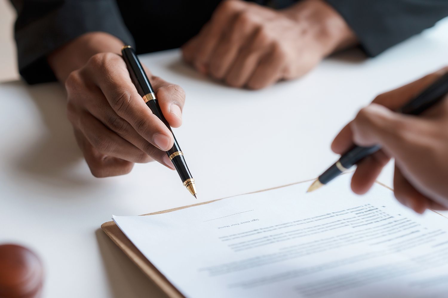 Hands holding pens, pointing at a document on a clipboard. Hands holding pens, pointing at a document on a clipboard.