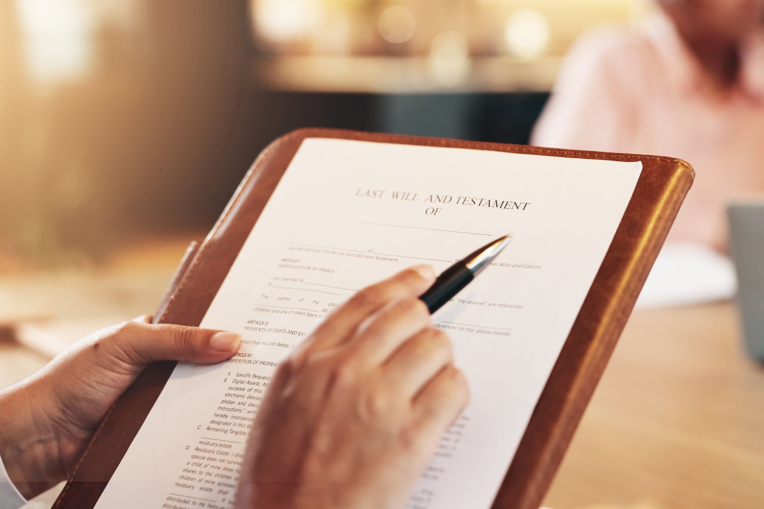 Person pointing with pen at document on wooden clipboard.