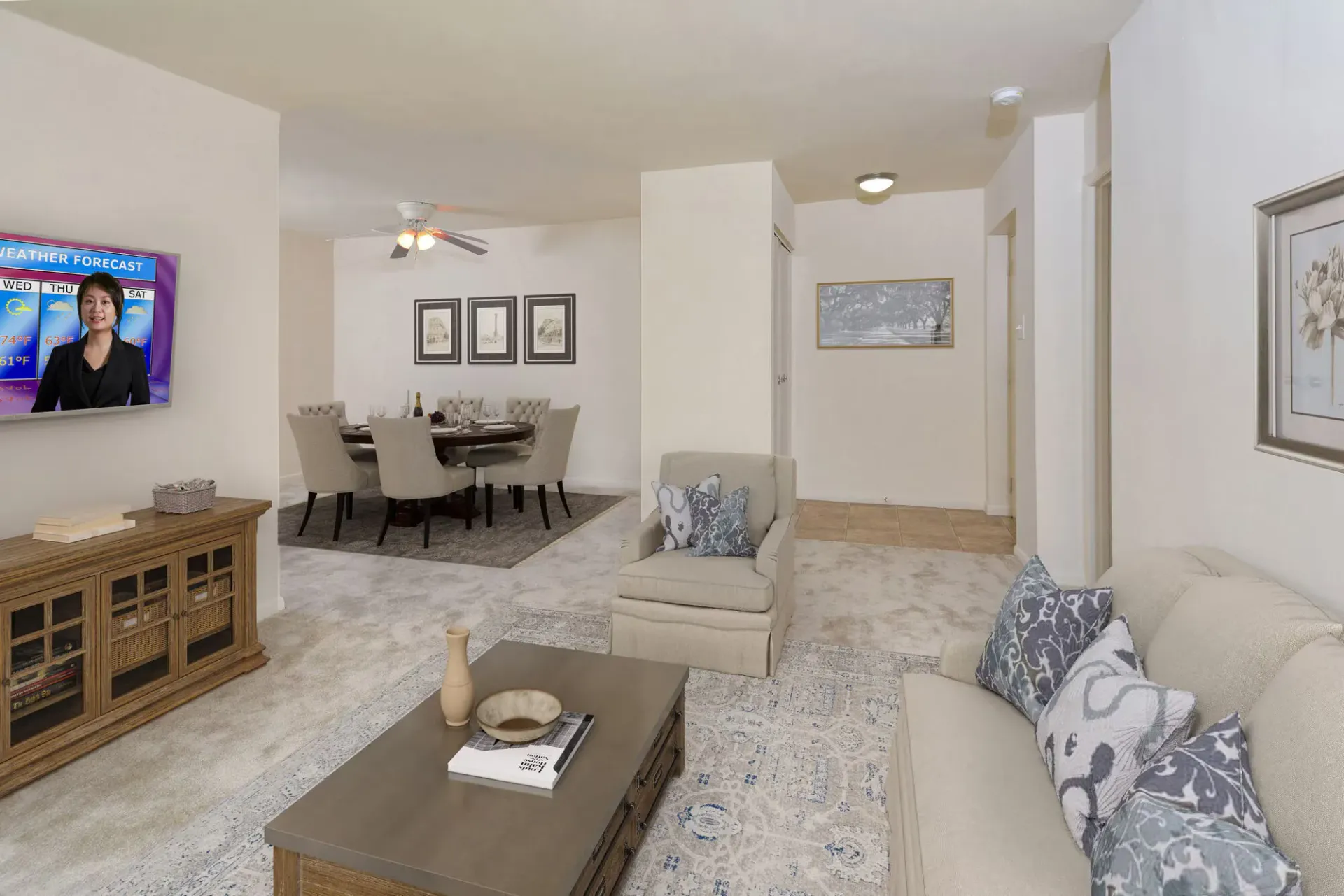 Living room and dining area in a beige-toned apartment with a TV and round dining table.