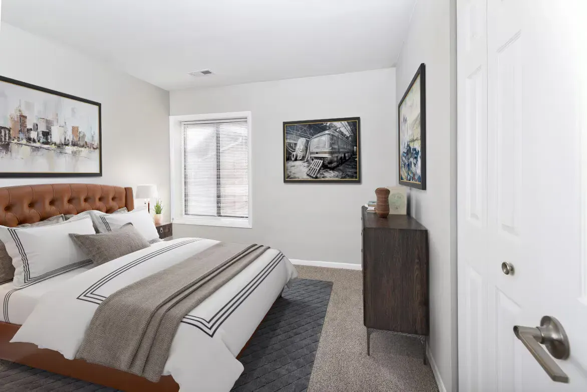 Bedroom in an apartment featuring a tufted brown headboard, bed, dresser, and wall art.