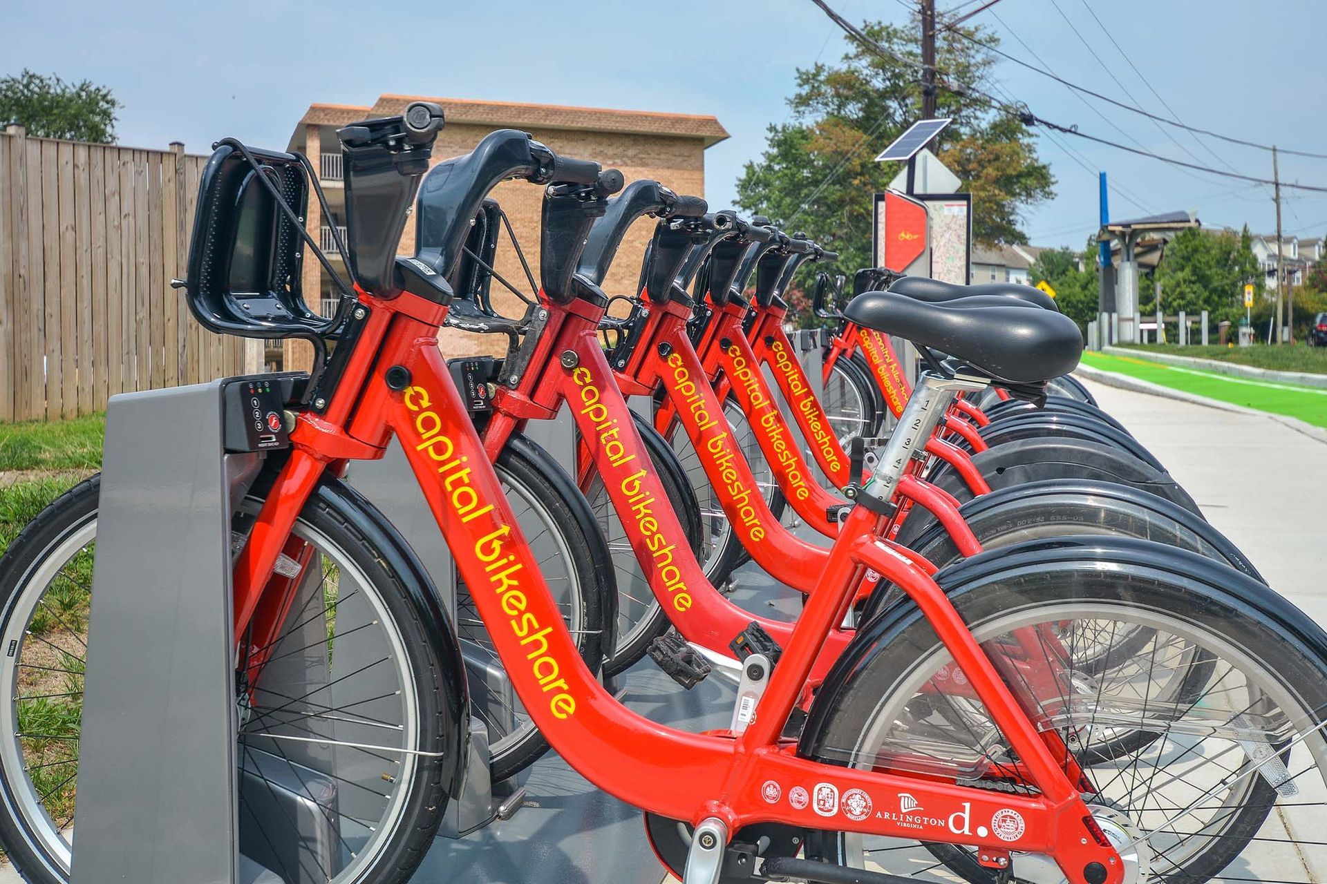 Row of red Capital Bikeshare bikes docked at a station along a sidewalk