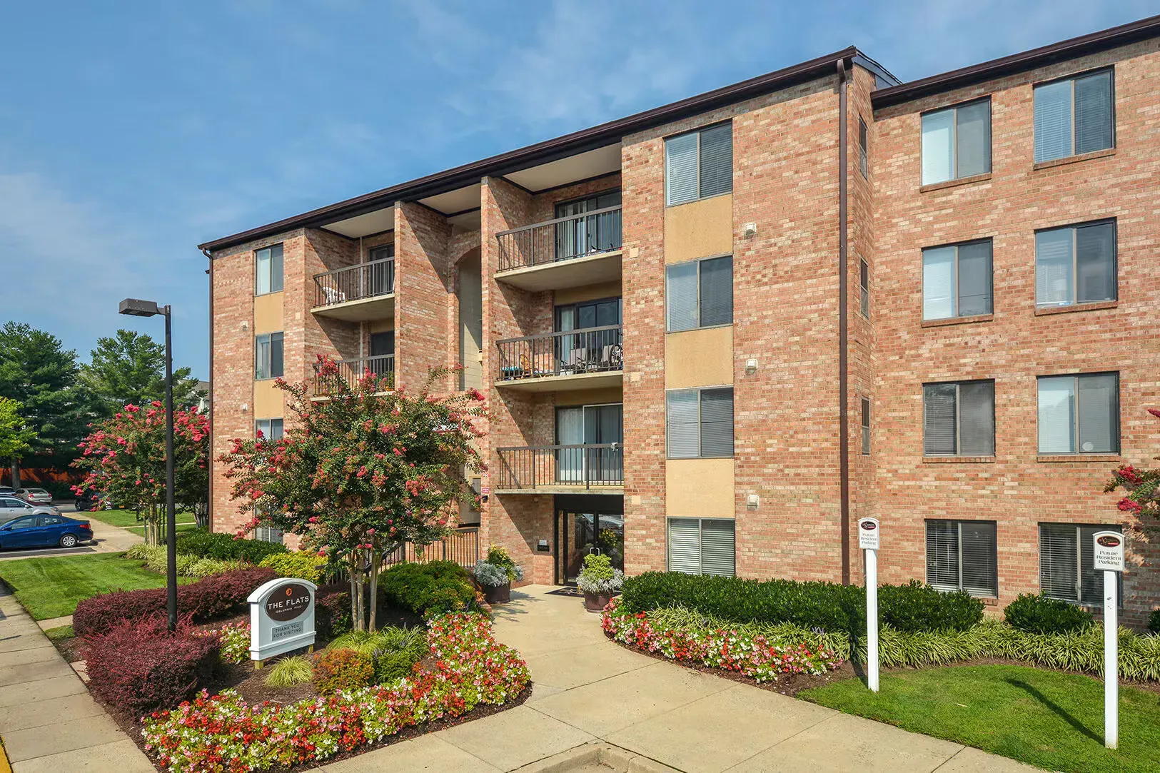 Exterior view of a brick apartment building with balconies and landscaped entry