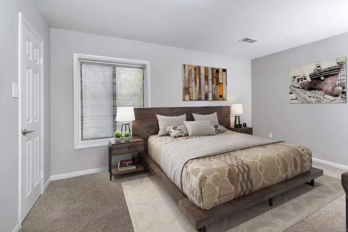 Modern bedroom in apartment with a wooden platform bed, two nightstands, and wall art.