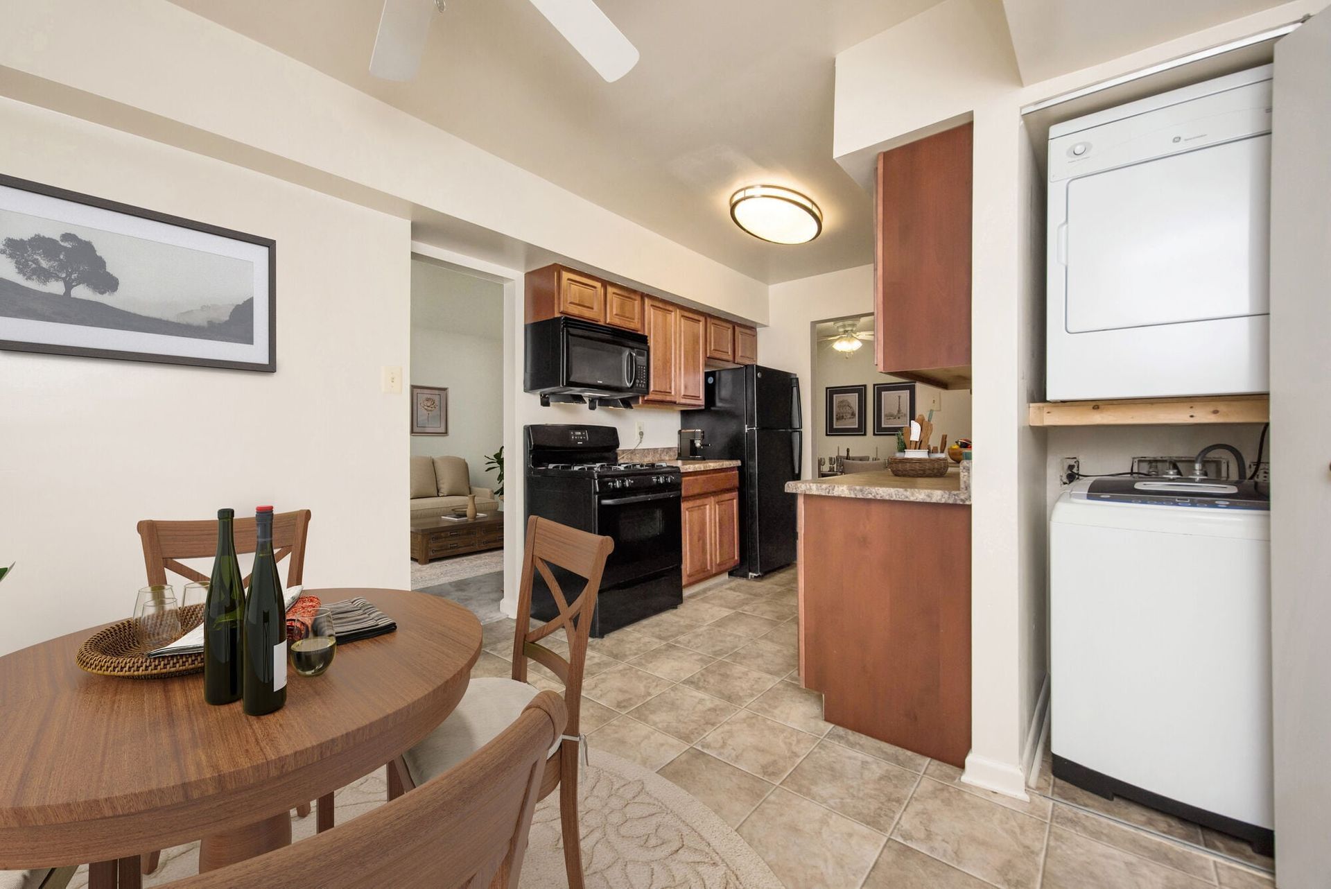 Open-concept kitchen with black appliances and a stacked washer/dryer beside a round dining table.
