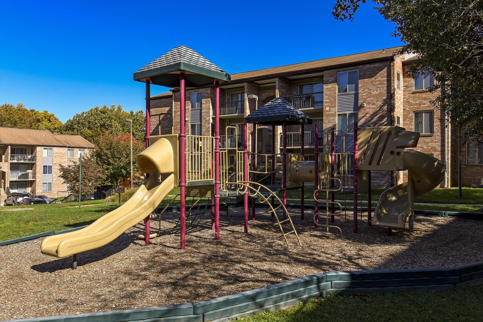 Playground with slides and climbing structures in a residential apartment courtyard.