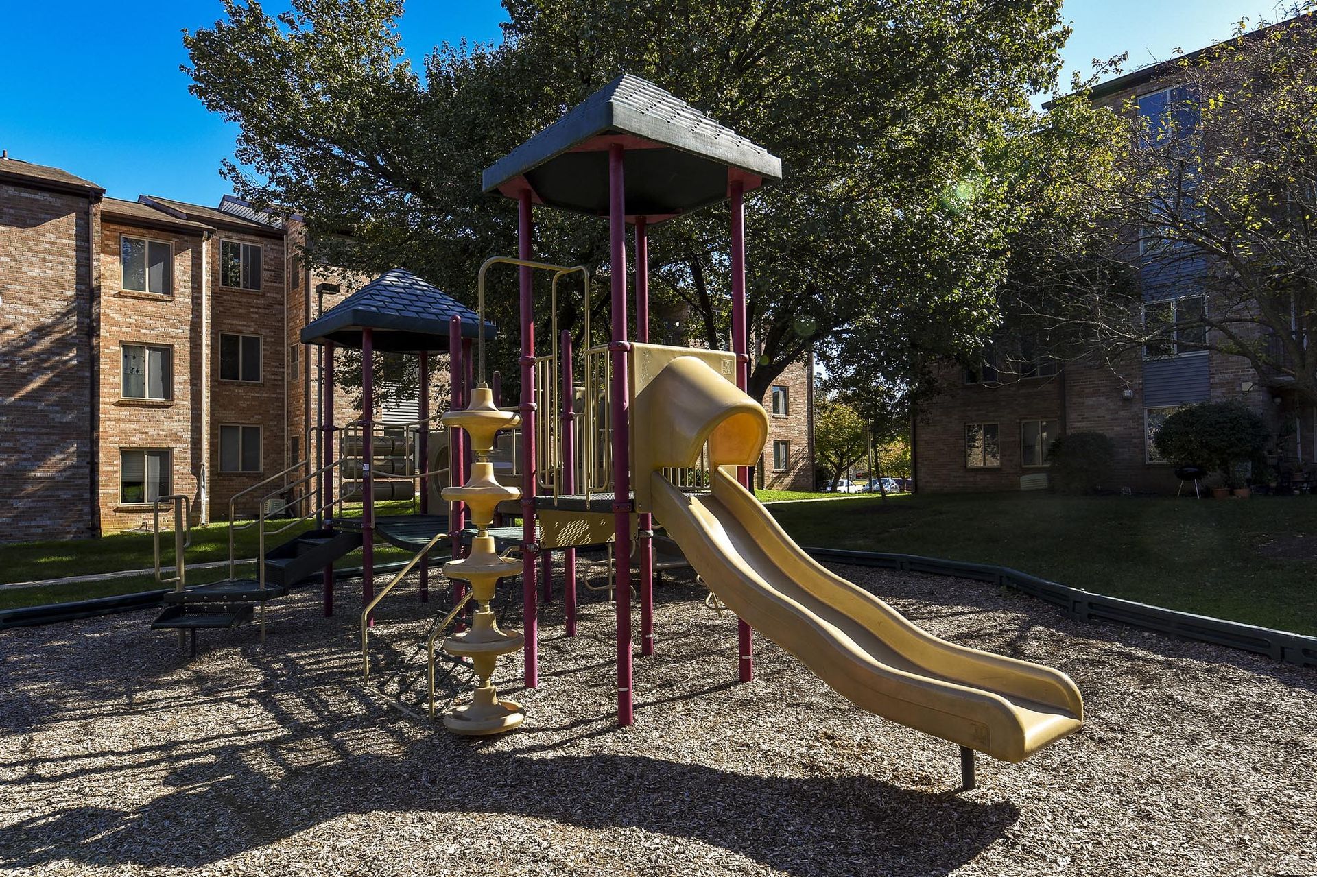Playground with slides and climbing structure in an apartment complex courtyard.