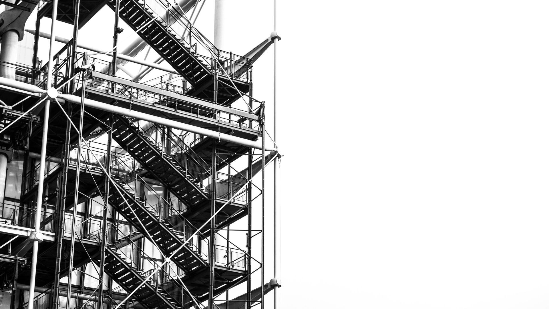 Black and white photo of industrial metal staircases on a building's exterior.
