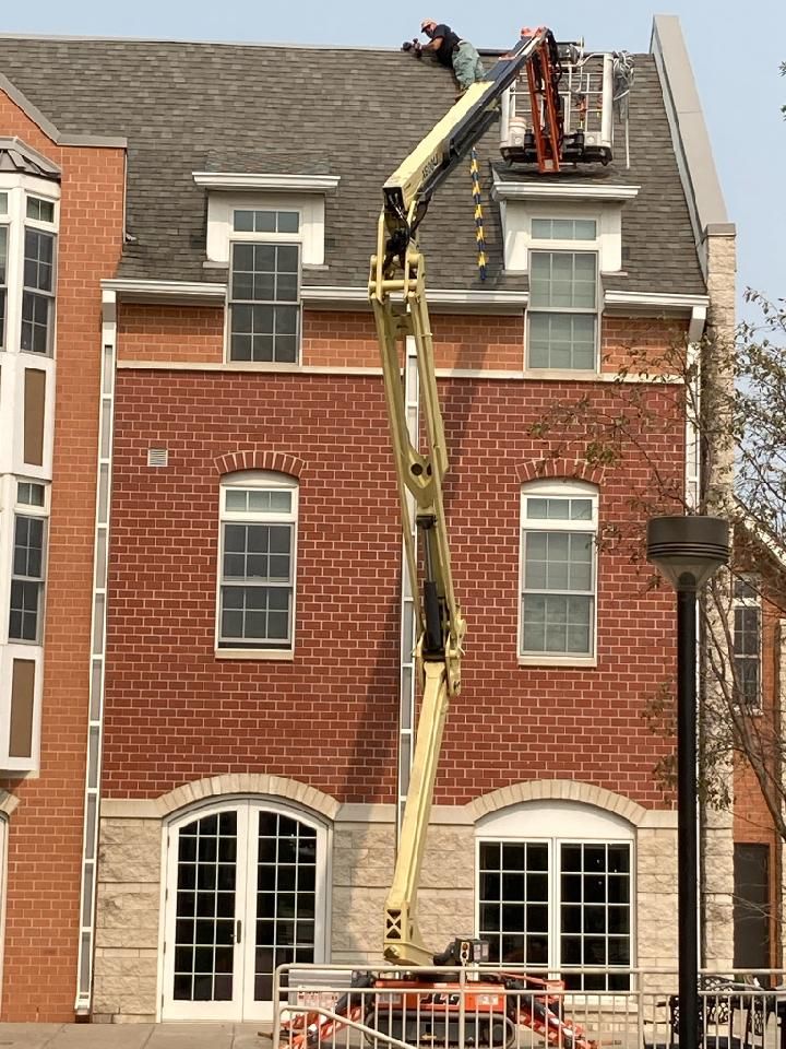 A worker in a lift repairs a building's roof