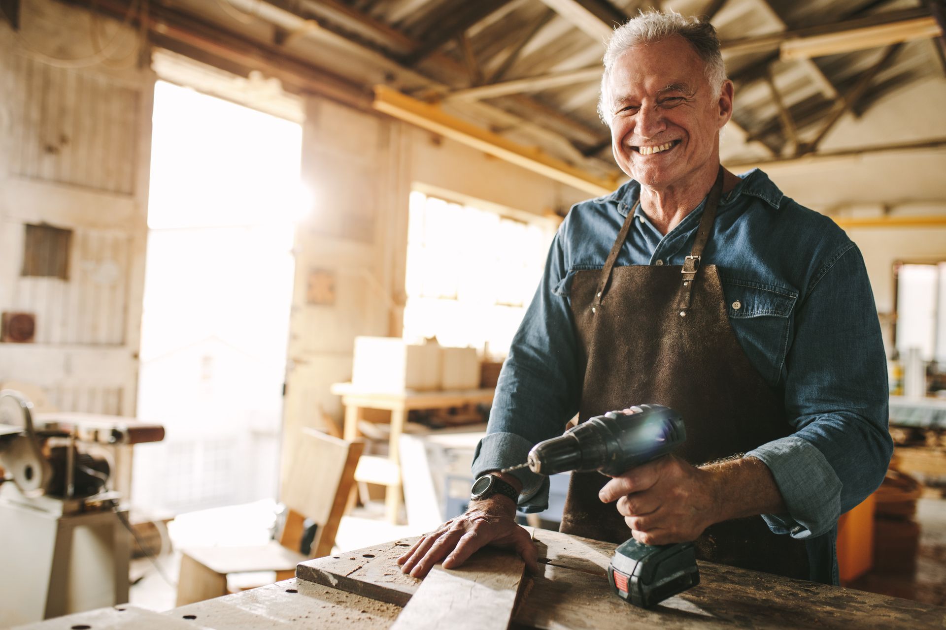 Man is Smiling While Holding a Drill in a Workshop — Naples, FL — Enduring Business Solutions, LLC