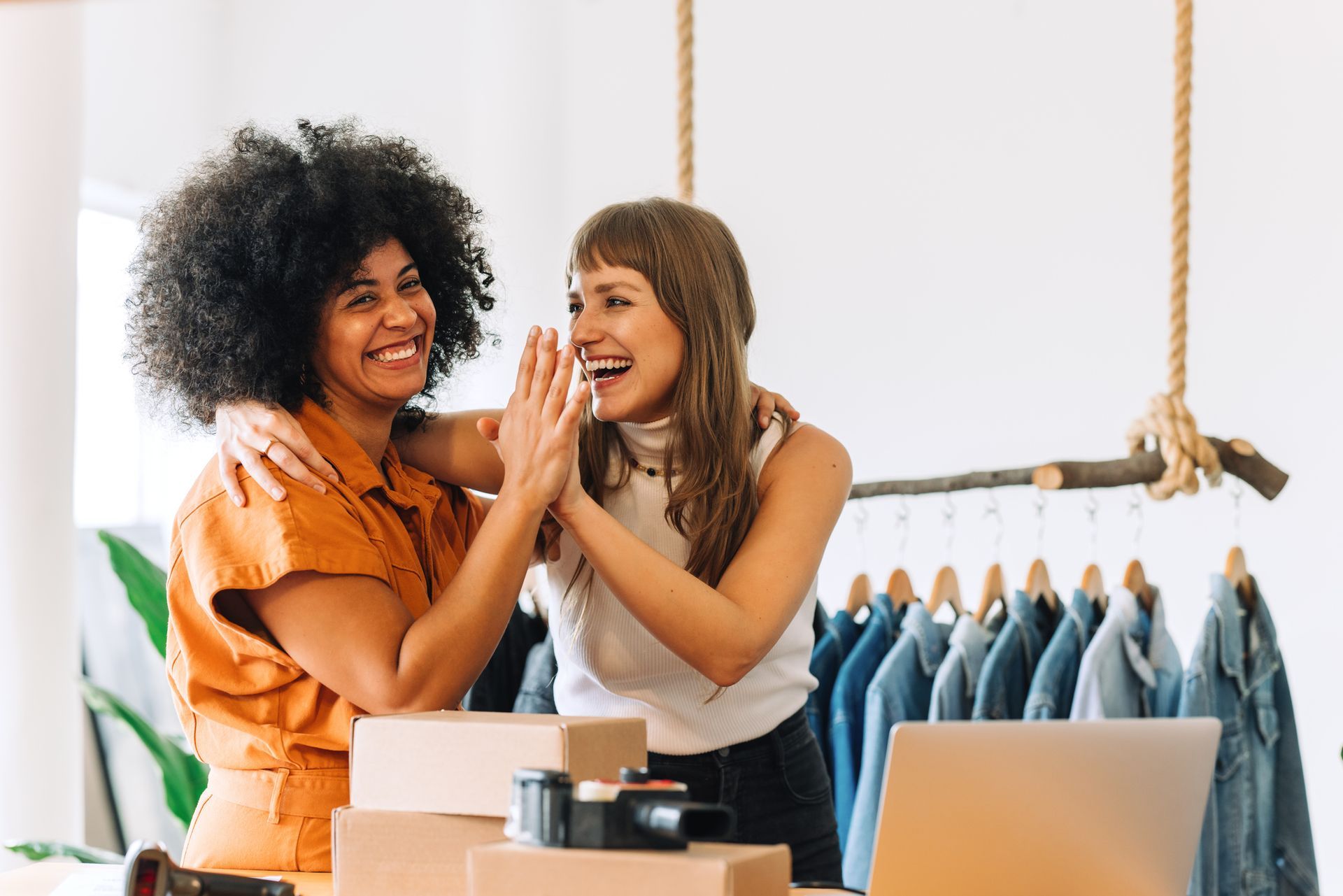 Two Women are Giving Each Other a High Five in a Clothing Store — Naples, FL — Enduring Business Solutions, LLC