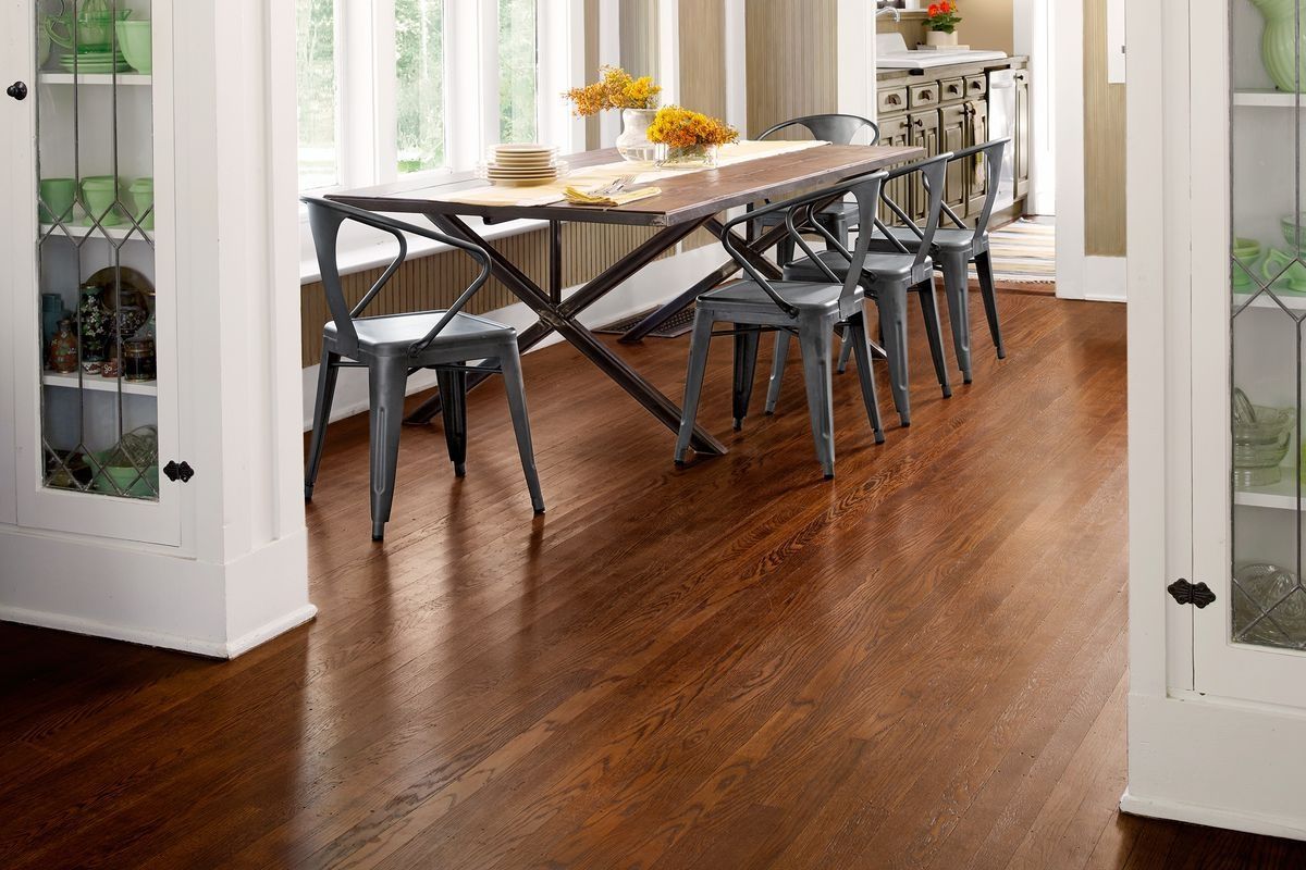 A dining room with hardwood floors and a table and chairs.