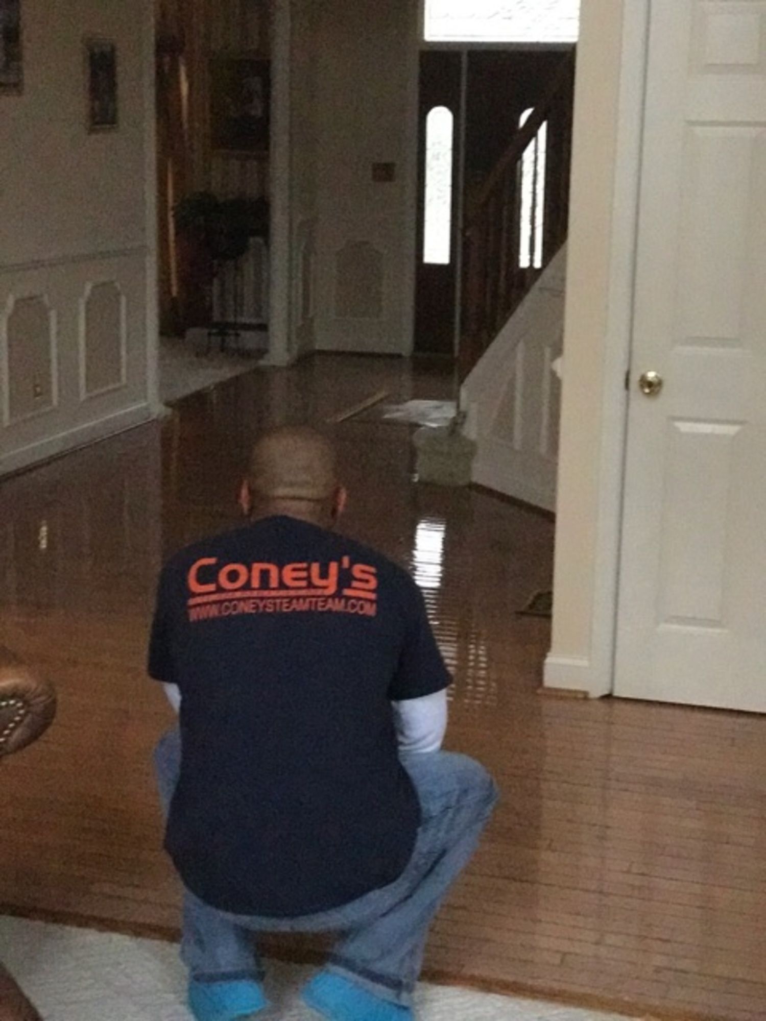 A man wearing a coney 's shirt is squatting down in a living room
