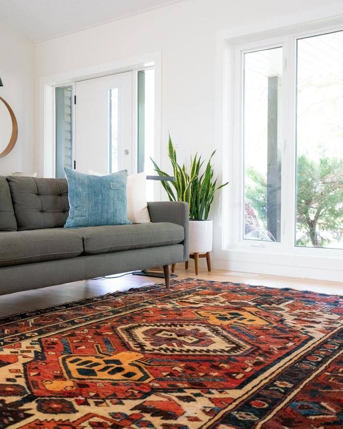 A living room with a couch , rug , and window.