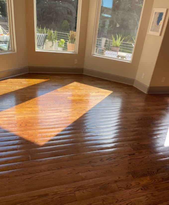 A living room with hardwood floors and two windows.