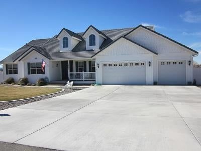 A large white house with a concrete driveway in front of it.