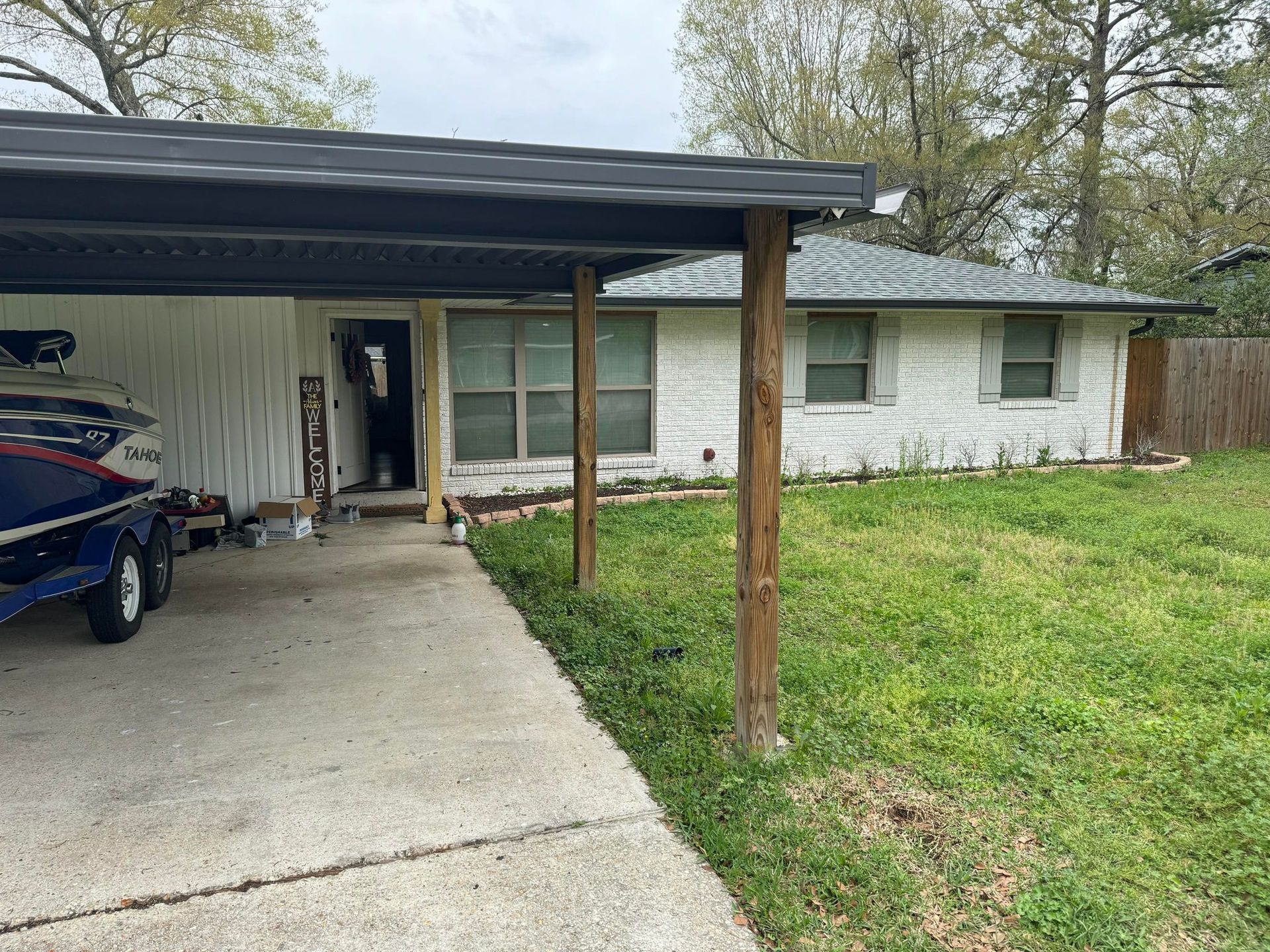 A boat is parked under a canopy in front of a house.