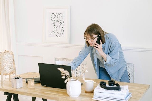 Person talking on a cell phone while using a laptop