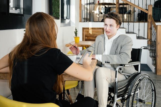 Two people sitting at a table, one is in a wheelchair 