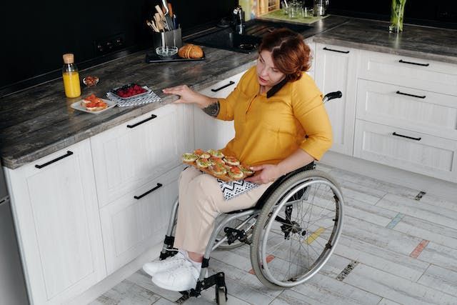 a person in a wheelchair talking on the phone in their kitchen