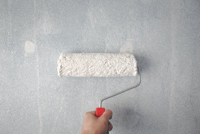 a person using a paint roller with white paint
