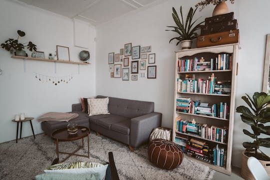 an apartment living room with a grey couch and a small bookshelf