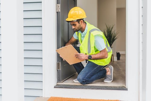 home inspector with a yellow hard hat and vest looking at a doorway
