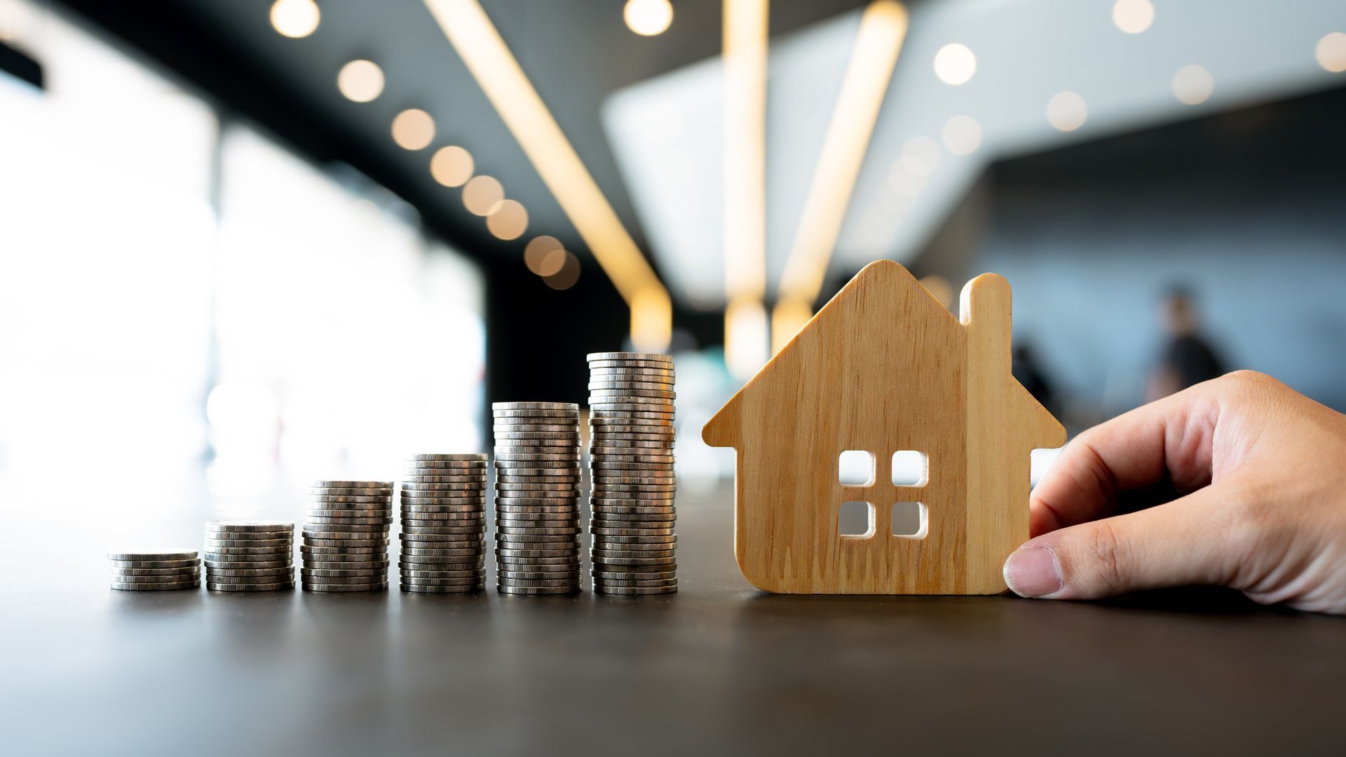 piles of coins next to house model
