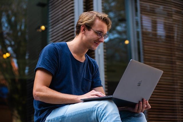 A person using a laptop and smiling.