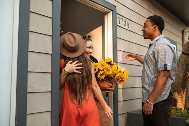 people hugging as they’re welcomed into a house