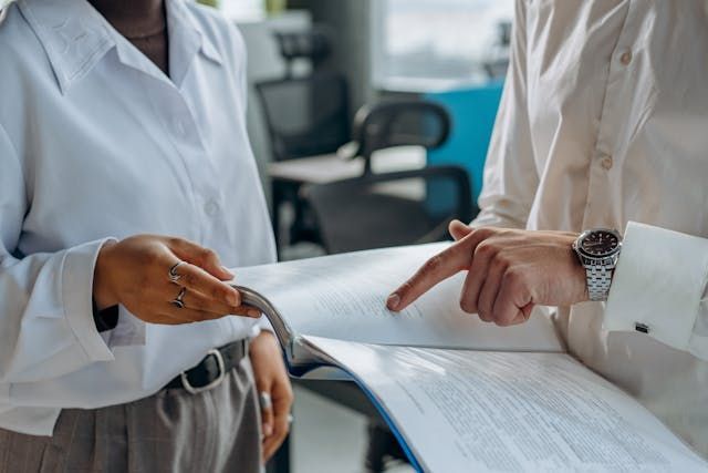 Two people holding paperwork and pointing at it