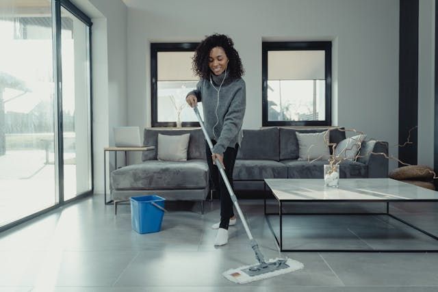 Person wearing headphones while mopping a living room floor